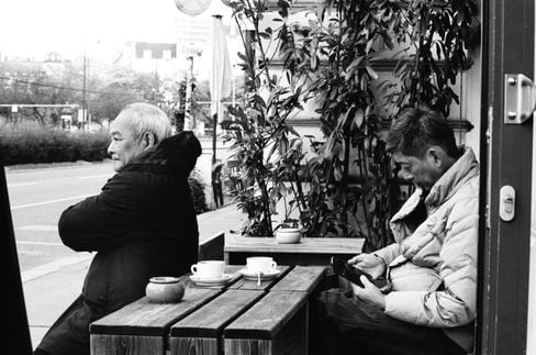 Two men sit outside of a coffee shop in Vienna, shot on film.